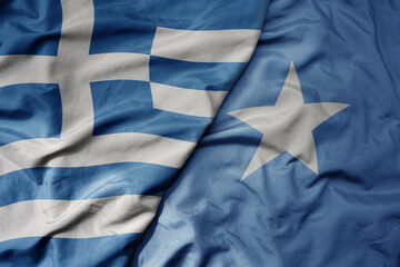 big waving national colorful flag of greece and national flag of somalia .