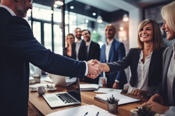 A business collaboration between two people is depicted in the image, with the man and woman smiling and shaking hands in their professional clothing, showing a successful job offer and a bright futu
