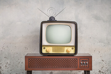 Old retro classic analog TV set and aged wooden television outdated amplifier front aged concrete wall background. Broadcasting, news concept. Vintage style filtered photo