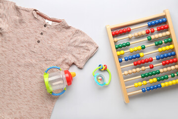 Baby clothes, toys and bottle on light background