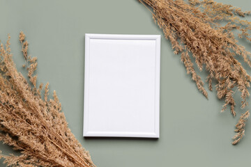Blank picture frame with pampas grass on green background