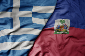 big waving national colorful flag of greece and national flag of haiti .