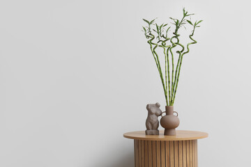 Vase with bamboo stems and decor on table near light wall