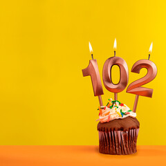 Candle with flame number 102 - Birthday card on yellow background