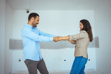 Obraz premium Dancing Couple Happy With Apartment Choice. Relocation, real estate, rent concept. Happy and Excited Young Couple Look Around In Wonder at their Newly Purchased
