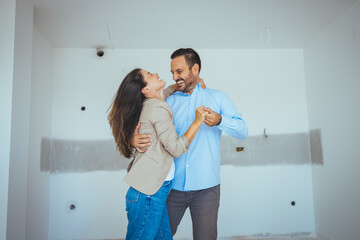 Dancing Couple Happy With Apartment Choice. Relocation, real estate, rent concept. Happy and Excited Young Couple Look Around In Wonder at their Newly Purchased