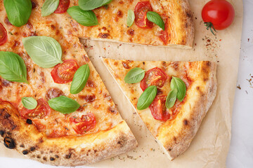 Baking paper with tasty pizza Margarita and basil on white background