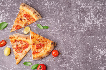 Pieces of tasty pizza Margarita with tomatoes and basil on dark table