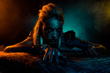 Portrait of terrifying north mythology viking girl blue yellow lights mist dead animal fur isolated on dark background