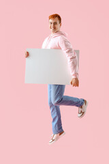 Jumping young man with blank poster on pink background