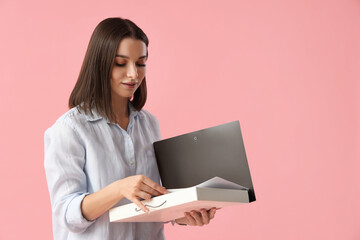 Young businesswoman with folder on pink background