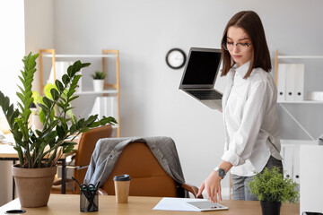 Young businesswoman with laptop and tablet computer working in office