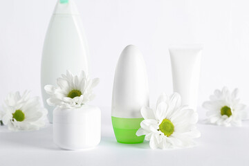 Different cosmetic products and chamomile flowers on white background