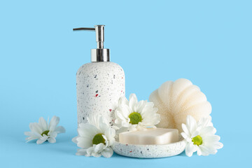 Bottle of cosmetic product, soap, bath sponge and chamomile flowers on color background