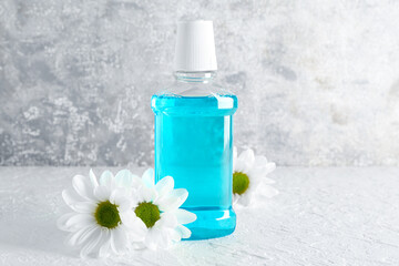 Obraz na płótnie Canvas Bottle of mouthwash and chamomile flowers on light table