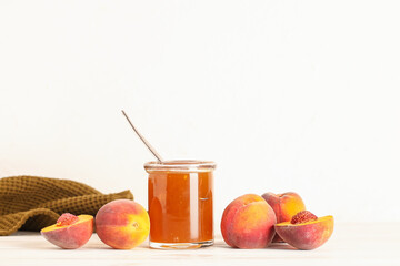 Jar with sweet peach jam and fresh fruits on table