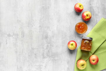 Glass bowl and jar of sweet apple jam on grunge background