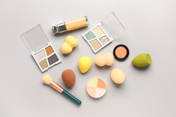 Composition with makeup sponges and decorative cosmetics on grey background