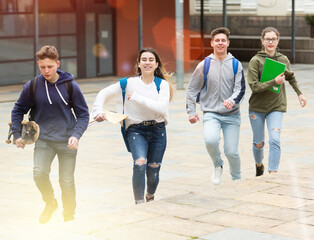 Obraz premium Group of teenage friends running as they leave the school building after lessons