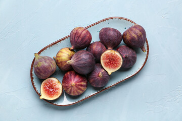 Plate with fresh ripe figs on blue background