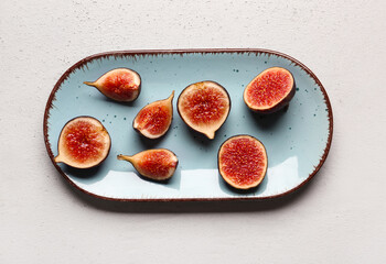 Plate with cut fresh figs on grey background