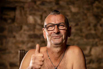 A satisfied middle-aged man with glasses smiles and looks playfully at the camera.
