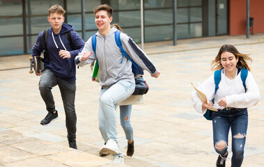 Group of teenage friends running as they leave the school building after lessons