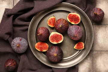 Plate with fresh ripe figs on grey tile background