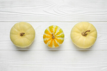 Different fresh pumpkins on white wooden background