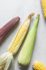 top view of peeled cob of corn on a marble table, overhead view of whole corn in green husk on a countertop, fresh organic sweet corn on table