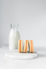 Vanilla sugar cookies with orange filling, round rosemary cookies filled with orange cream, no spread cookies on a marble tray with a white background