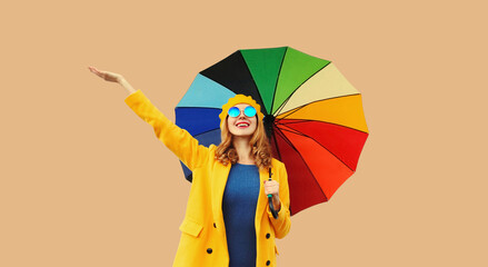 Autumn color style outfit, beautiful happy cheerful young woman holds colorful umbrella enjoys new season in french beret hat, coat on beige studio background
