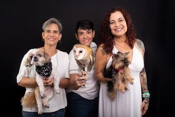 Three happy, confident lesbian women with their pets. An owl and Yorkshire and Shih Tzu dogs.