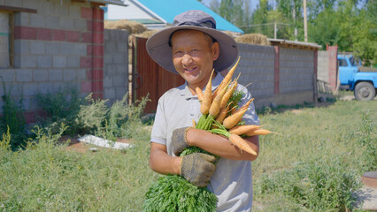 A man walks cuddly embracing an armful of carrots