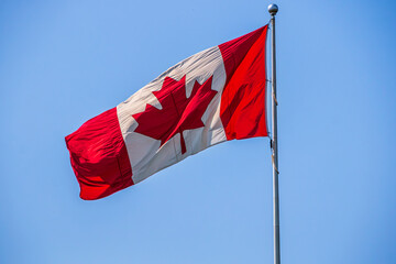 canadian flag waving against blue sky