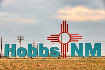  City entrance sign with large turquoise colored letters and large Zia sign