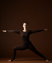 Fototapeta na wymiar portrait of a woman in yoga poses on a brown background.a woman professionally demonstrates yoga poses and gestures in brown sportswear on a brown background