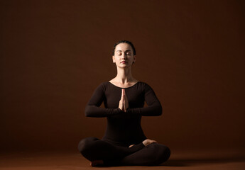 portrait of a woman in yoga poses on a brown background.a woman professionally demonstrates yoga poses and gestures in brown sportswear on a brown background