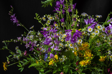 Beautiful bouquet of wildflowers on a black background. Blur and selective focus