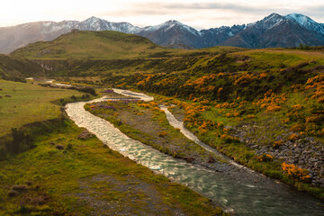 mountain valley river in the mountains at sunrise with snow capped mountains in the background