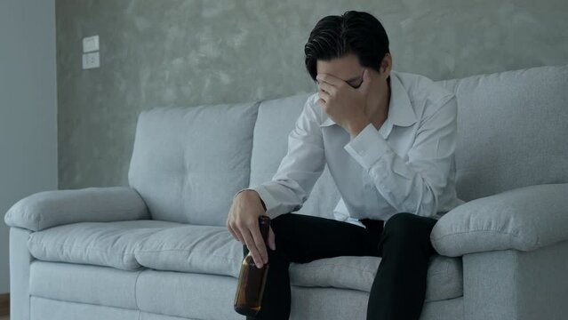 Depressed young business man addicted feeling bad drinking whiskey alone at home, stressed frustrated lonely drinking alcohol suffers from problematic liquor, alcoholism, life and family problems