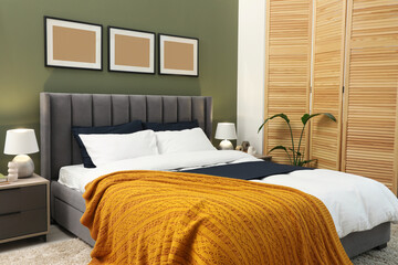 Large comfortable bed, houseplant and lamps in stylish room. Interior design