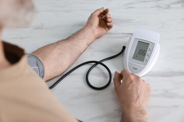 Man measuring blood pressure at white marble table, closeup