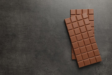 Delicious milk chocolate bars on black table, flat lay. Space for text