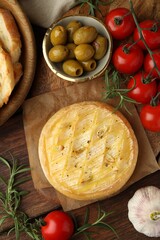 Tasty baked brie cheese served on wooden table, flat lay