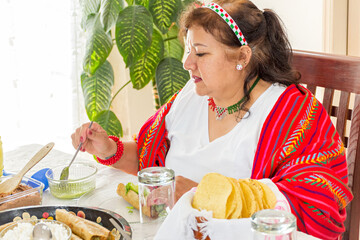 Adult woman putting cheese and sauce to her taco during a family dinner to celebrate mexican independence day