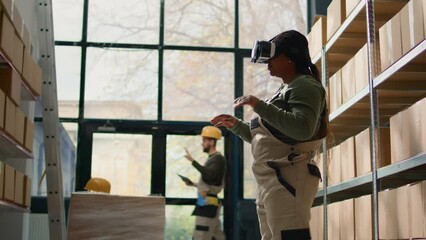 Manager in warehouse wearing VR goggles, using technology to visualize how to best stack cardboard boxes on shelves to make room for more. Supervisor in storage hub uses virtual reality - Powered by Adobe