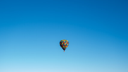 wide angle capture of hot air balloon on blue background in the sky
