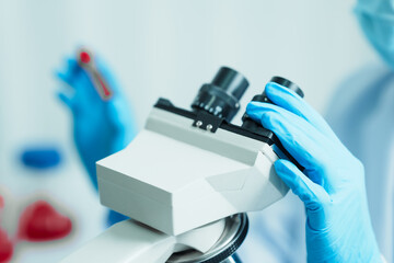 Close up dedicated hematology lab technician scrutinizing blood sample analysis under microscope,...