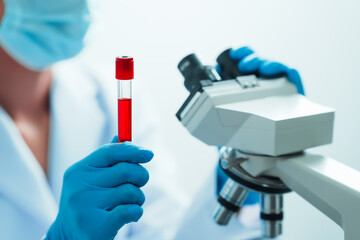 Close up dedicated hematology lab technician scrutinizing blood sample analysis under microscope,...